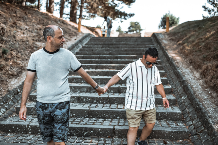 Male Holding Hands And Helping Brother With Down Syndrome | Taybron Law Firm